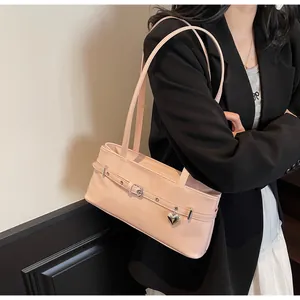 Détail du sac sous le bras en cuir verni rose clair avec breloque cœur argentée et boucle