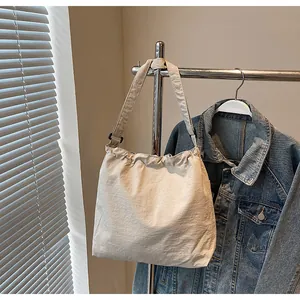 Détail du sac seau en nylon beige avec fermeture plissée à cordon et bandoulière