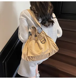 Macro view of khaki pleated drawstring shoulder bag with black metal D-ring detail