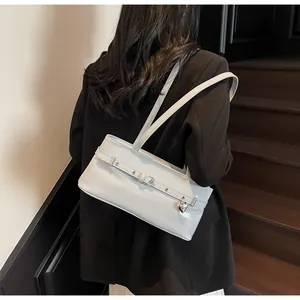 Sac sous le bras blanc brillant avec breloque cœur porté sur un blazer noir chic
