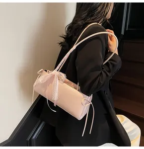 Detail of light pink glossy shoulder bag featuring a white lace bow and elegant ribbons