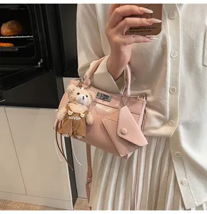 Detail of light pink patent leather handbag featuring a cute bear plush charm and metal lock