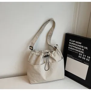 Détail du sac seau en nylon beige montrant la fermeture à cordon et la texture de la poche