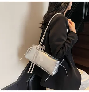 Detailed view of silver shoulder bag with metallic finish and lace bow decoration