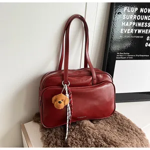 Detailed macro of dark red leather Boston bag featuring silver logo and plush dog charm