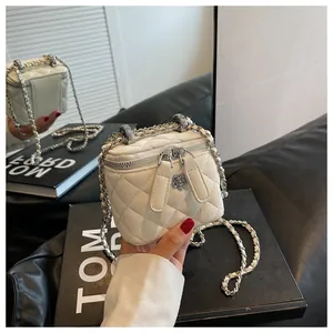 Dettaglio mini borsa bianca trapuntata con ciondolo a fiore argento e catena in metallo