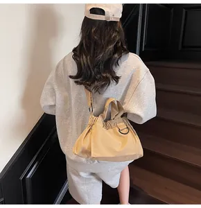 Khaki canvas bucket bag with drawstring closure and thick strap shown on stairs