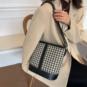 Fashionable houndstooth bucket bag with black leather stitching and white decorative seams