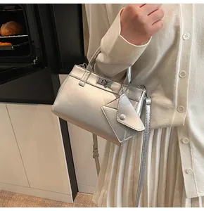 Close-up of silver crossbody bag with a square metal clasp and mini envelope pouch