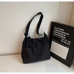 Détail du sac seau en nylon noir avec cordon de serrage et deux poches avant larges