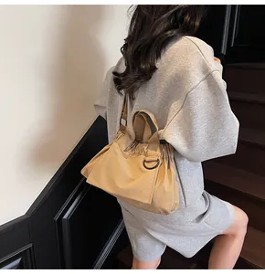 Detail view of khaki pleated shoulder bag with drawstrings and black D-ring accents