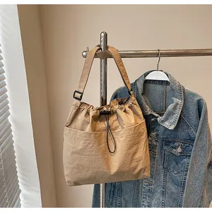 Détail du sac à bandoulière en nylon kaki avec cordon de serrage et poche frontale
