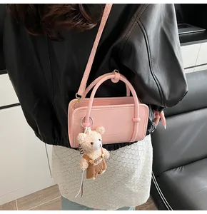 Sac bandoulière rose avec pendentif ours porté par un mannequin en cuir noir