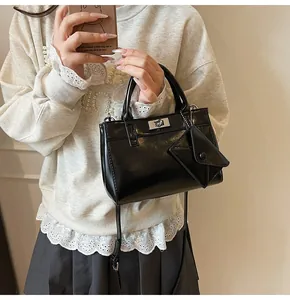 Detail of black glossy handbag with silver twist lock and triangular coin purse attachment