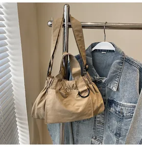 Close-up of khaki pleated nylon tote bag with metal D-ring hanging on a silver hanger