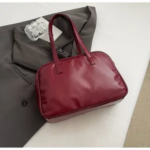 Detailed top view of a dark red faux leather Boston bag on a grey suit jacket