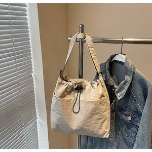 Détail du sac à bandoulière en nylon crème avec cordon de serrage et plis