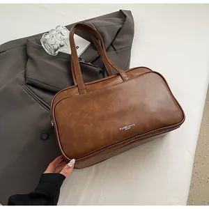 Detail of caramel brown Boston bag showing luxury PU leather texture and brand logo