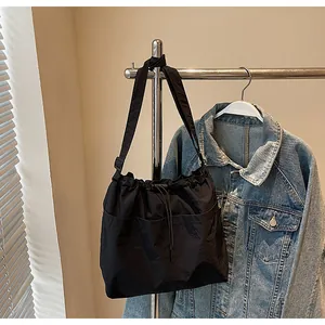Détail du sac seau noir en nylon avec cordon de serrage et bandoulière nouée réglable