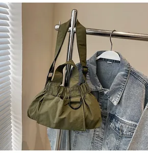 Detail of army green nylon pleated bucket bag with metal D-ring and adjustable strap