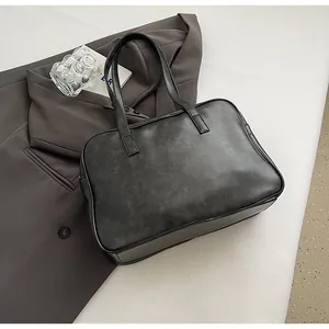 Detail of black vintage leather Boston bag with long handles and sleek zipper closure