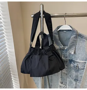 Detail of black pleated crossbody bag with front pocket and metal D-ring attachment