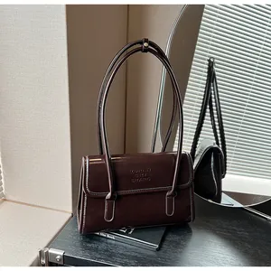 Detailed view of dark brown glossy leather shoulder bag with embossed logo and chic straps