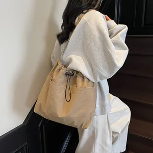 Grand sac seau en nylon beige avec cordon de serrage et bandoulière ajustable