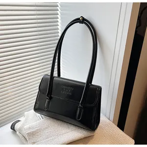 Detail of black faux leather shoulder bag with embossed text on textured fabric