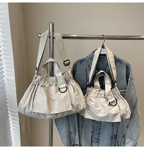 Detail of off-white crossbody bag set with pleated drawstring and D-ring hardware