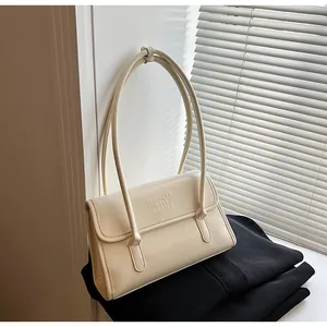 Detail showing the embossed MUHETI SHI SHANG lettering on the cream leather shoulder bag