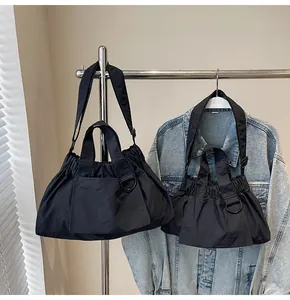 Detail showing two sizes of black nylon shoulder bags with drawstring pleats and D-ring