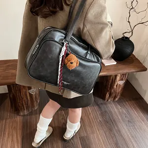 Large black Boston bag in matte faux leather with plush pendant for elegant women