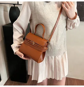Détail d'un sac bandoulière en cuir marron avec ceinture décorative et boucle dorée