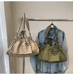 Detail of khaki and green pleated nylon bags showing drawstring texture and D-ring