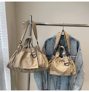 Macro shot of khaki nylon tote bag set with pleated design and metallic D-ring details