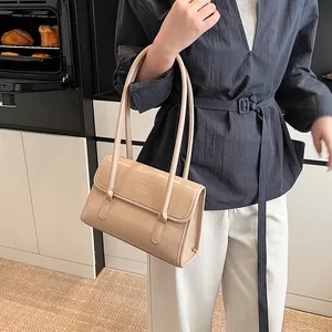 Minimalist beige leather shoulder bag with embossed letters in a modern kitchen setting