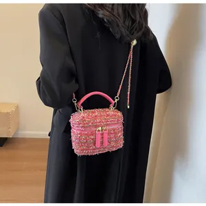 Détail du sac boîte en tweed rose avec chaîne dorée porté par un mannequin en manteau