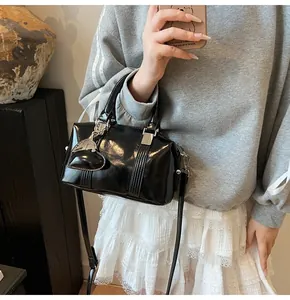 Detailed view of black patent leather Boston bag with heart charm and detachable strap