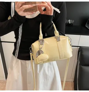 Detail of cream Boston bag with glossy finish and silver heart pendant decoration