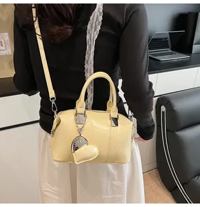 Close-up of cream leather Boston bag featuring a heart pendant with CLEARLY engraving