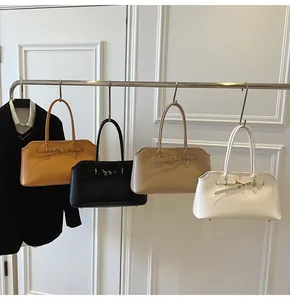 Close-up of stylish handbags in orange, black, beige, and white with gold hardware detail