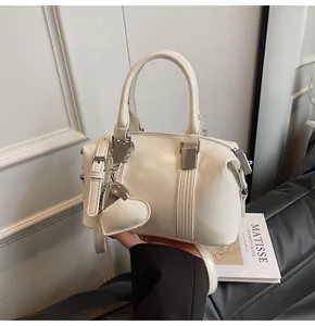 Close-up of a white glossy Boston bag with silver hardware and a heart leather charm