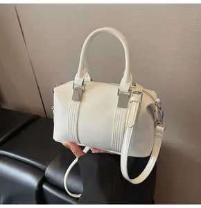 Detail of white glossy patent leather Boston bag with silver metal buckles and top handles