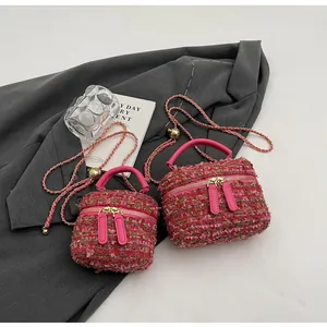 Détail du sac seau en tweed magenta avec chaîne dorée sur fond de blazer gris