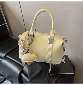 Close-up of cream Boston bag with silver hardware and engraved heart pendant detail