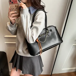 Minimalist black leather tote bag with stylish orange rope and gold chain accessories
