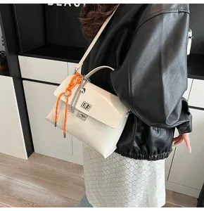 Close-up of white glossy flap bag with metal twist locks and orange rope detail