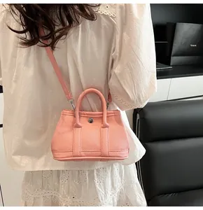 Detalle de bolso de cuero granulado rosa con cierre giratorio metálico plateado