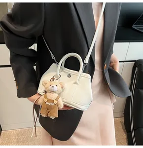 Detalle de mini bolso blanco con grabado de lichi y un tierno oso de peluche en el asa